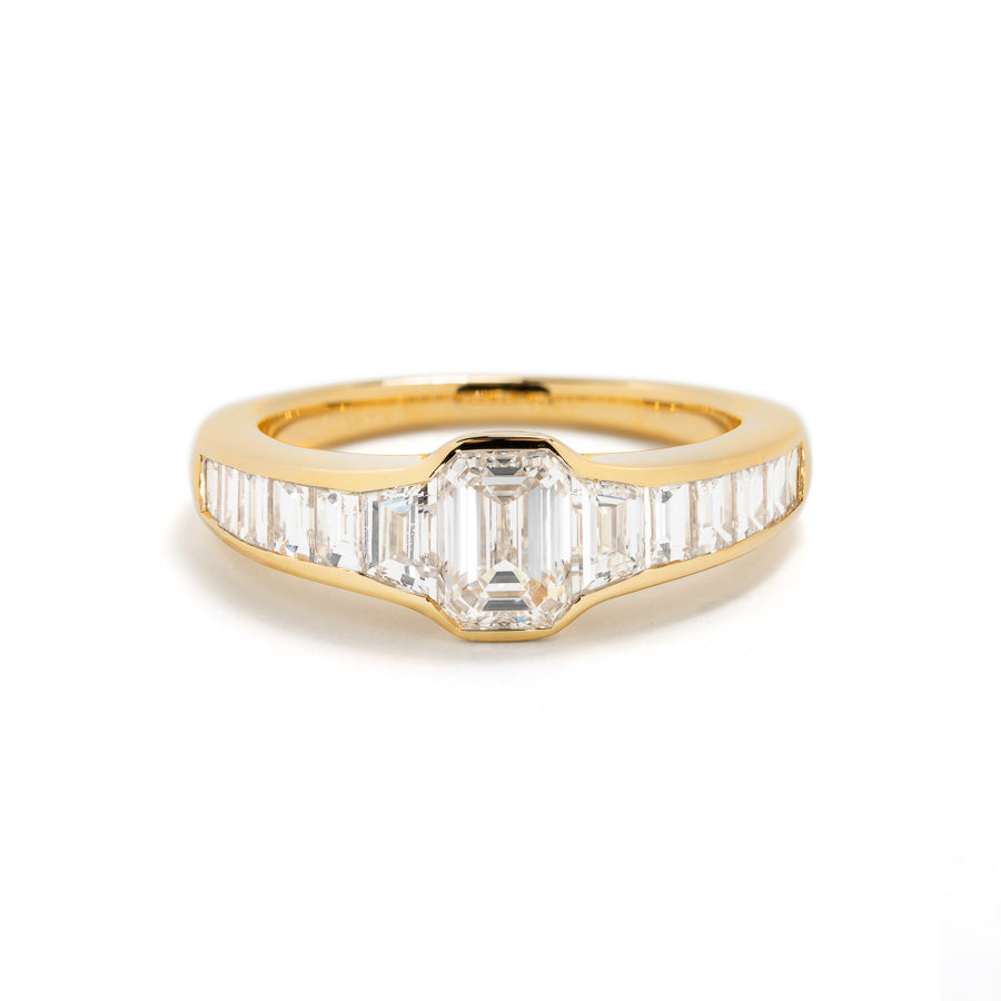 Diamantring i 18 kt. gulguld prydet med en 0,90 ct. smaragdsleben River(E)VVS2 diamant, flankeret af 2 smaragdslebne River(E)/VVS diamanter, i alt 0,40 ct. samt 10 smaragdslebne Top Wesselton/VVS-VS diamanter, i alt 0,72 ct. GIA certifikat medfølger. Findes også i 18 kt. hvidguld med 2,38 ct. smaragdslebne diamanter til kr. 144.500,-