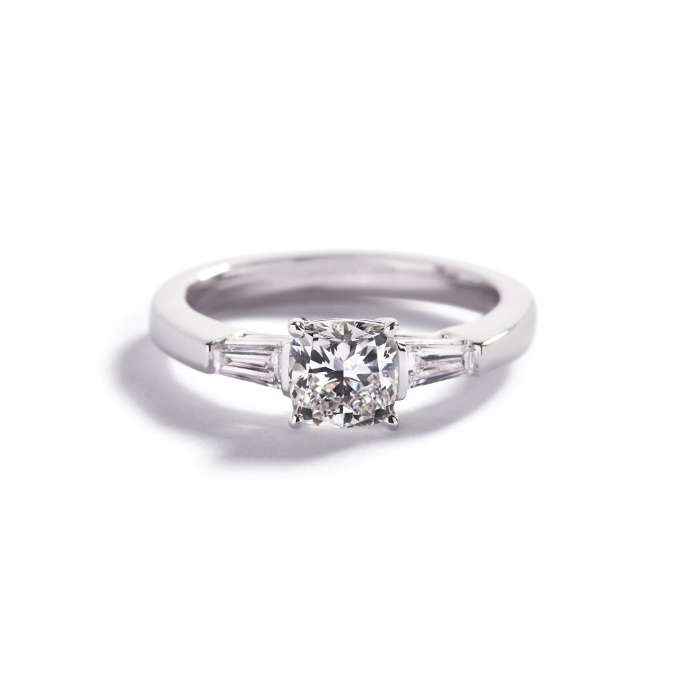 3-stens ring i 18 kt. hvidguld prydet med en 1,01 ct. cushion-cut Top Wesselton(F)/VVS2 diamant flankeret af 2 baguetteslebne Top Wesselton/VVS-VS diamanter, i alt 0,24 ct.

GIA certifikat medfølger.