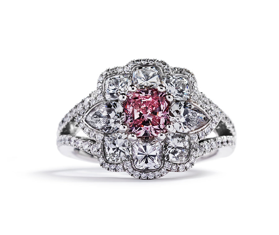Rosetring i 18 kt. hvidguld prydet med en 0,79 ct. radiant-cut Natural Fancy Intense Pink/P1 diamant flankeret af to dråbeslebne Top Wesselton/SI diamanter  samt seks cushion-cut Top Wesselton/SI diamanter, i alt 1,94 ct. omkranset af 106 River/VVS brillanter, i alt 0,48 ct.