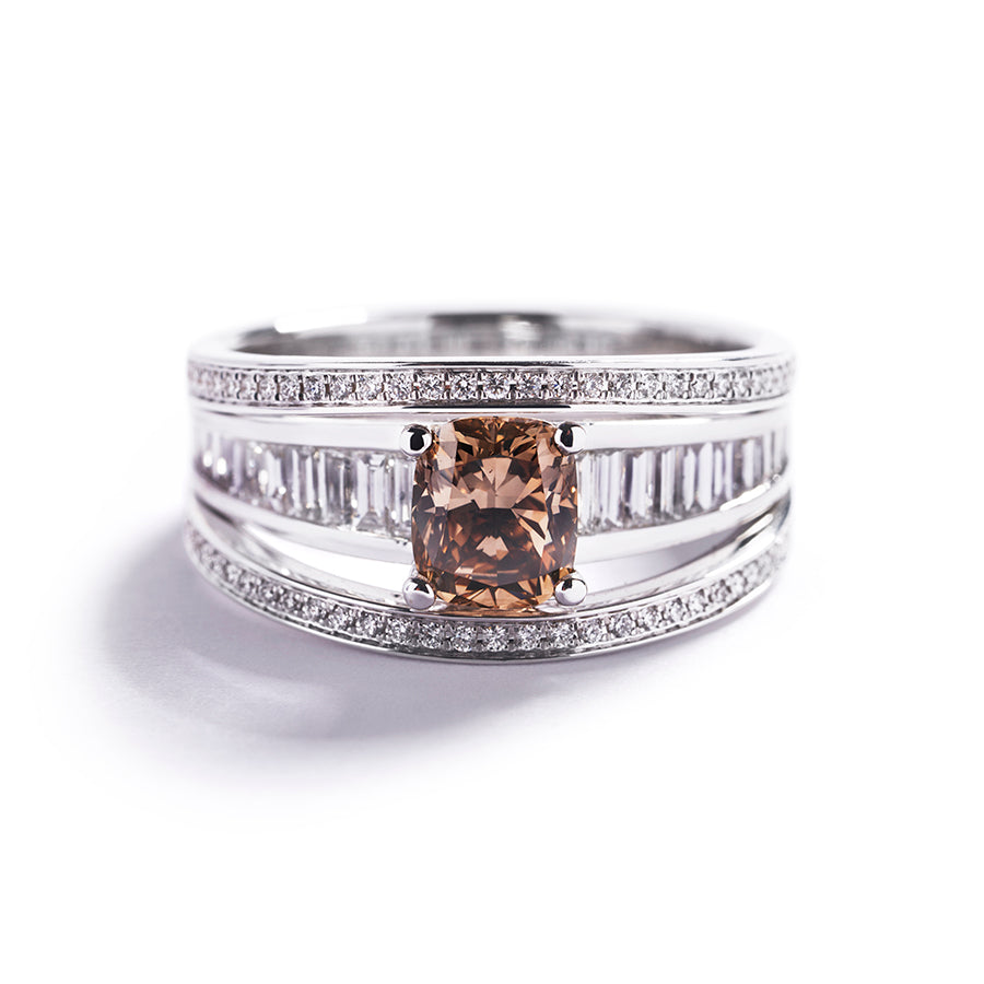 Bred diamantring i 18 kt. hvidguld prydet med en 1,19 ct. champagnefarvet Natural Fancy Deep Yellow Brown/VS diamant samt 24 smaragdslebne Top Wesselton/VVS-VS diamanter, i alt 0.96 ct. og to rækker med 70 VVS/VS brillanter, i alt 0,29 ct.